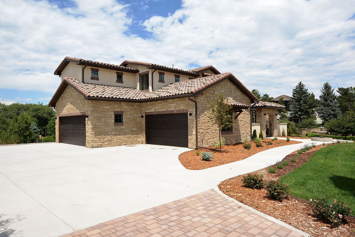The front of the stone home with a three-car garage and paver driveway