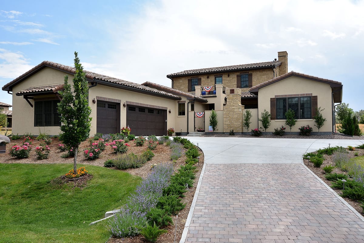 The stone home seen along its landscaped paver drive
