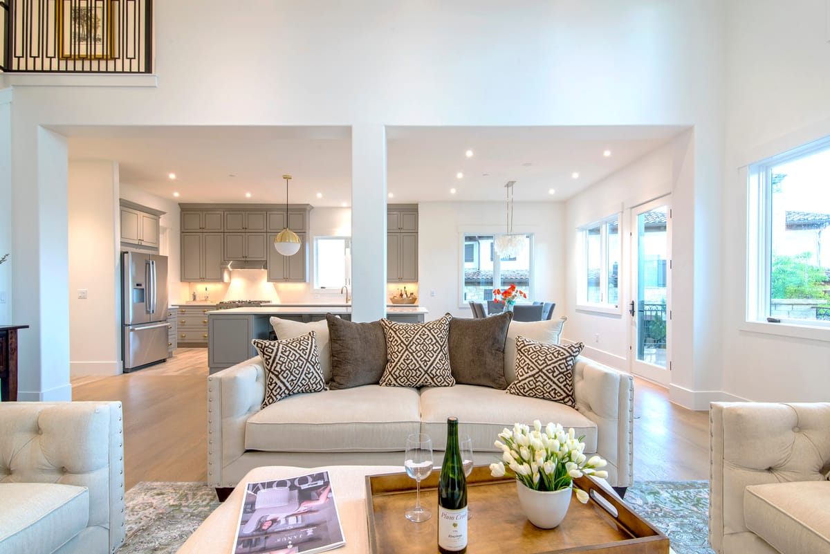 An open living room and kitchen with white sofas and a wood floor
