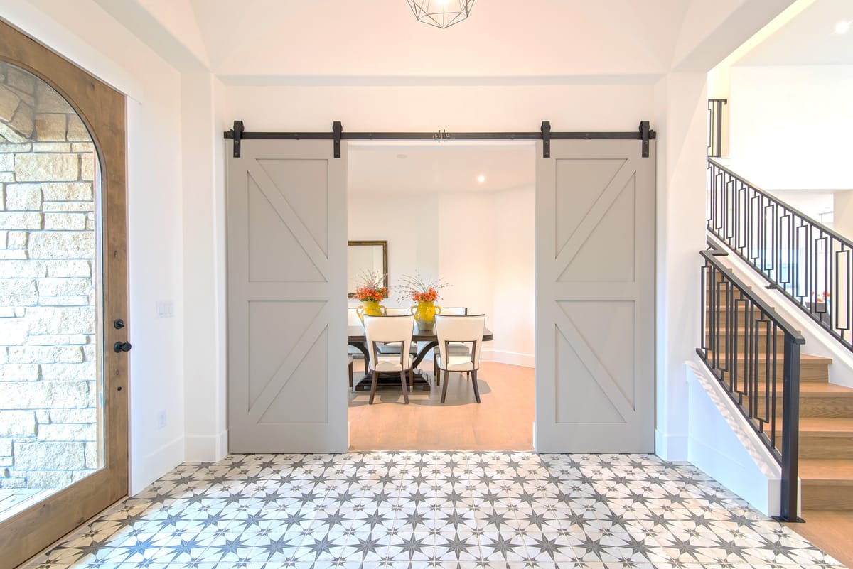 A tiled entry hall with sliding barn doors opening to the dining room
