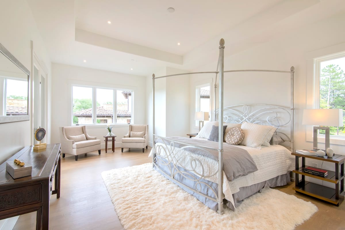 A main bedroom with a four-poster bed and a seating area by the windows