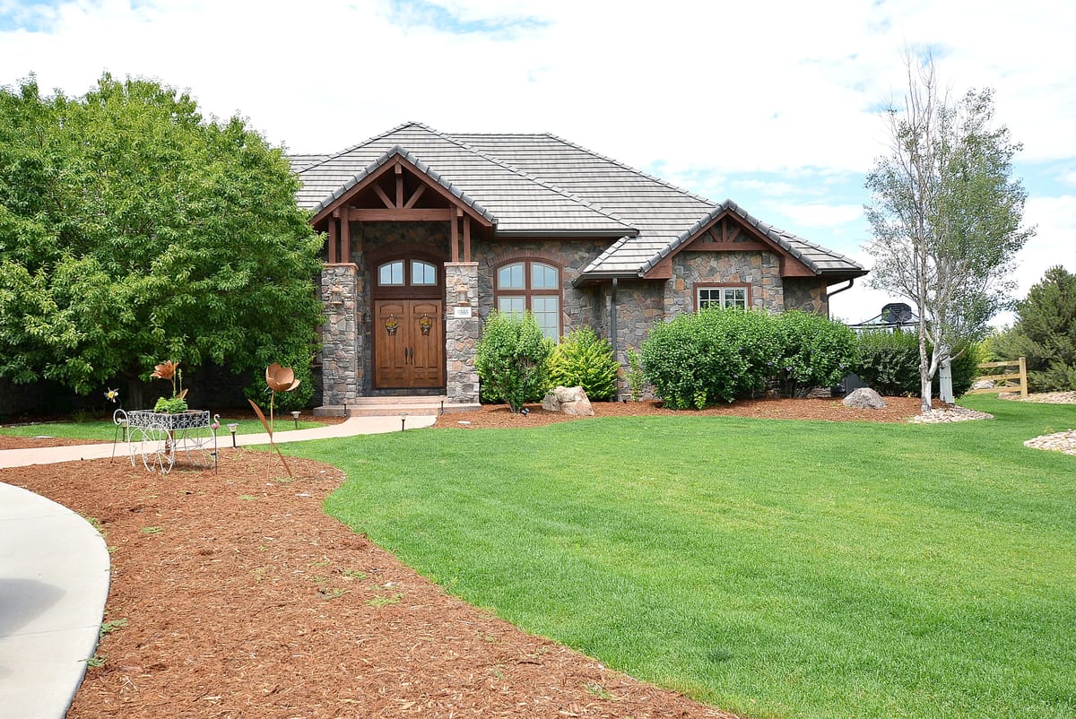 The timber-framed entry of the home at the end of a mulched walk