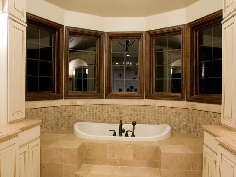 A bathroom with a tub set into a bay of leaded windows