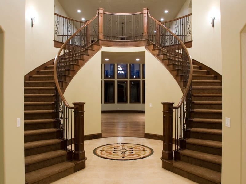 A curved double staircase rising from a tiled entry hall