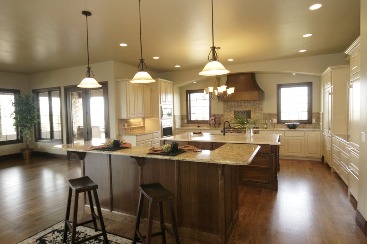 A kitchen with two islands, bar stools and a range hood