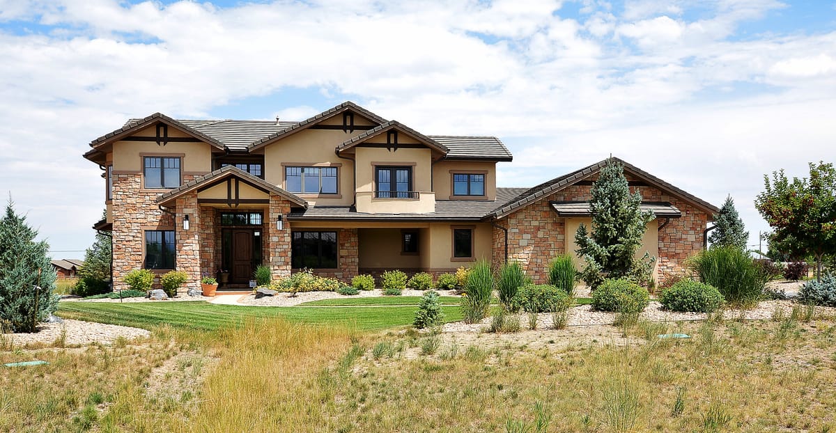 A stone and timber home behind a native grass front garden