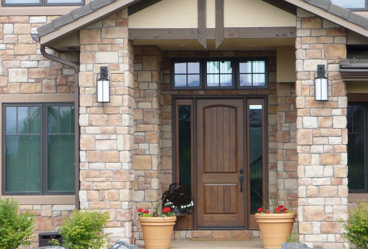 The covered front entry, with a wooden door between stone columns and planters