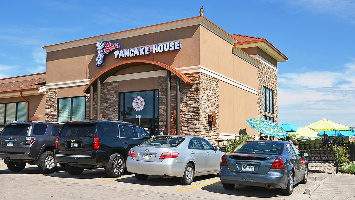 A pancake house restaurant with cars parked in front