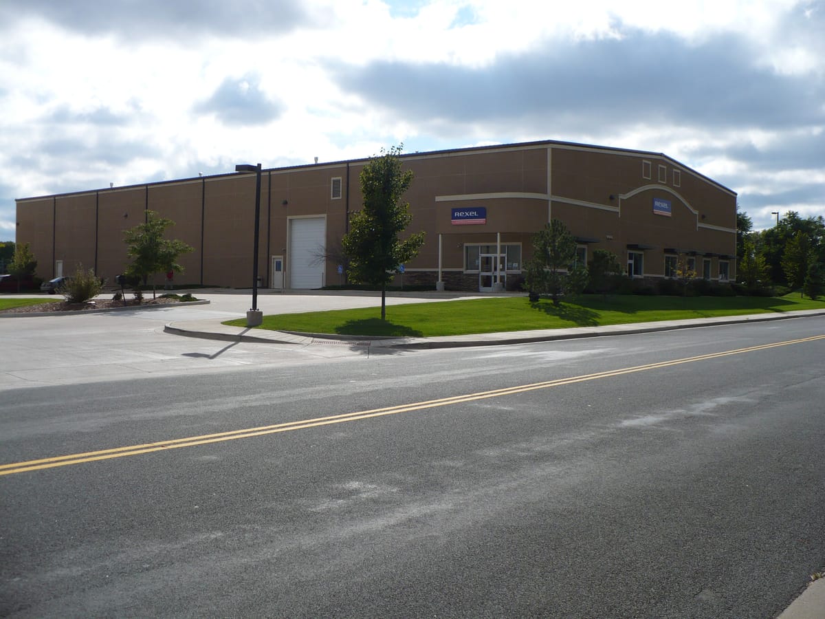 A large warehouse on a corner lot under an overcast sky