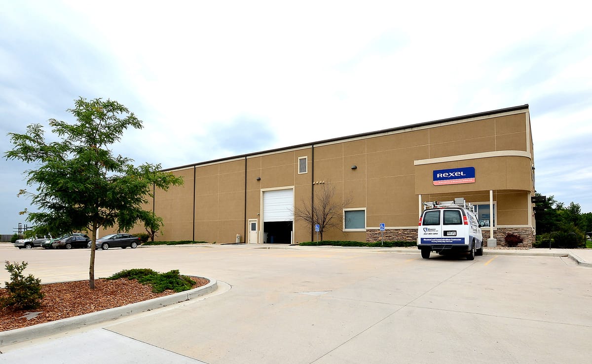 The long side elevation of the warehouse behind a young tree