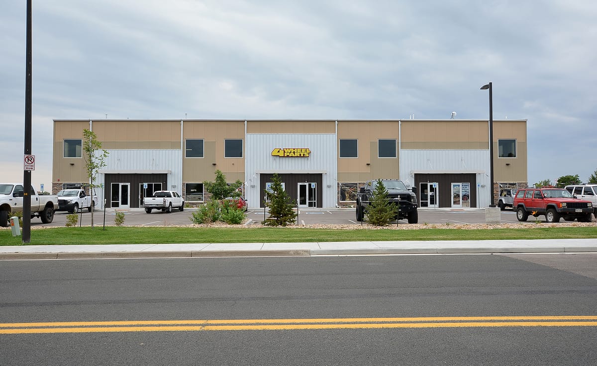 The street frontage of the warehouse, with tenant signage and parking