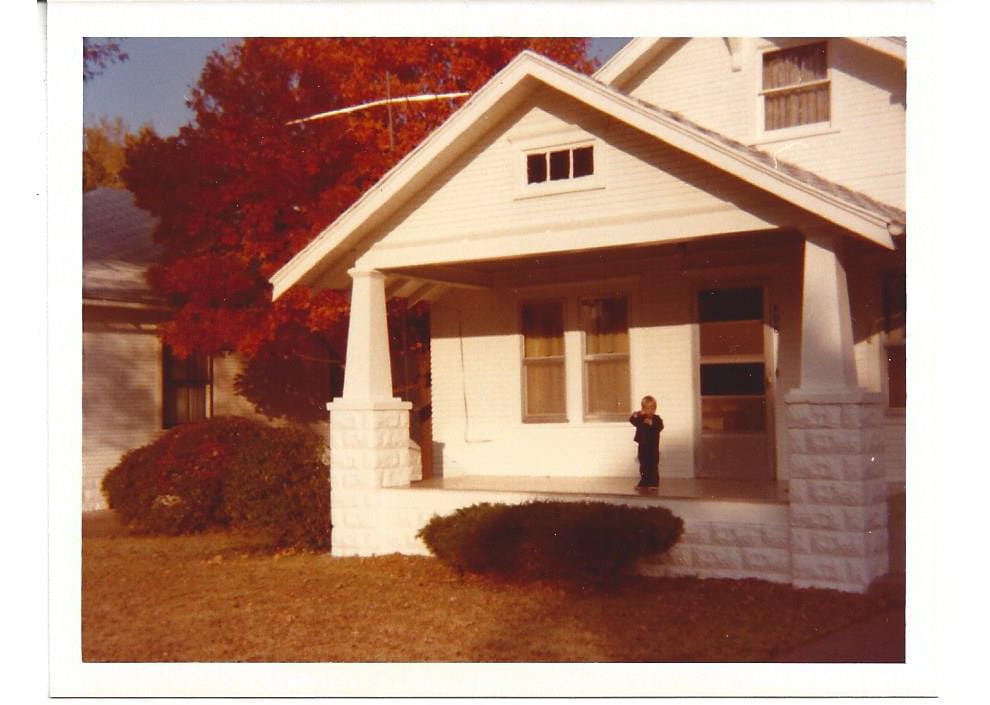 A single-storey house with a covered porch, framed by a red maple, built in 1976