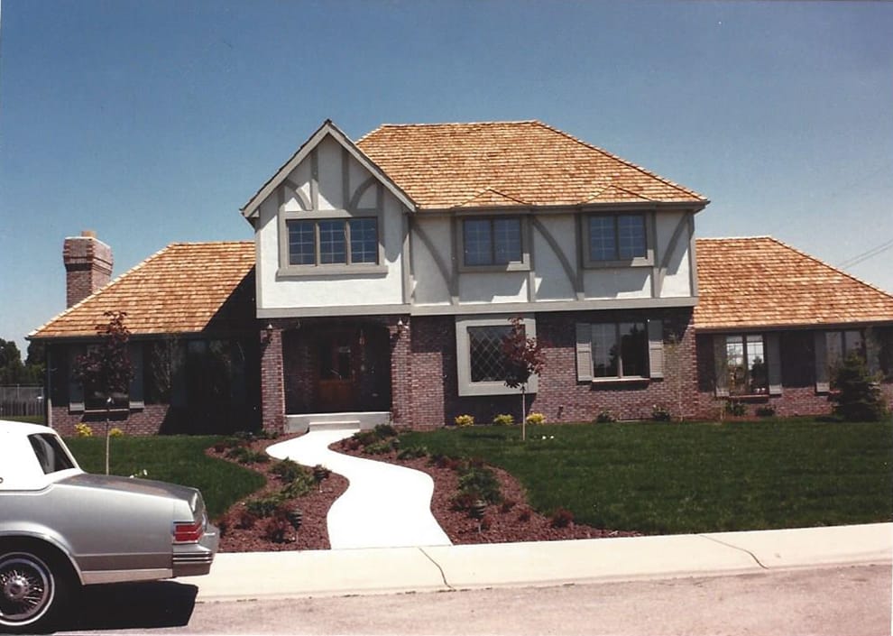 A two-storey shingled home with a brick front and a curved walk, built in 1986