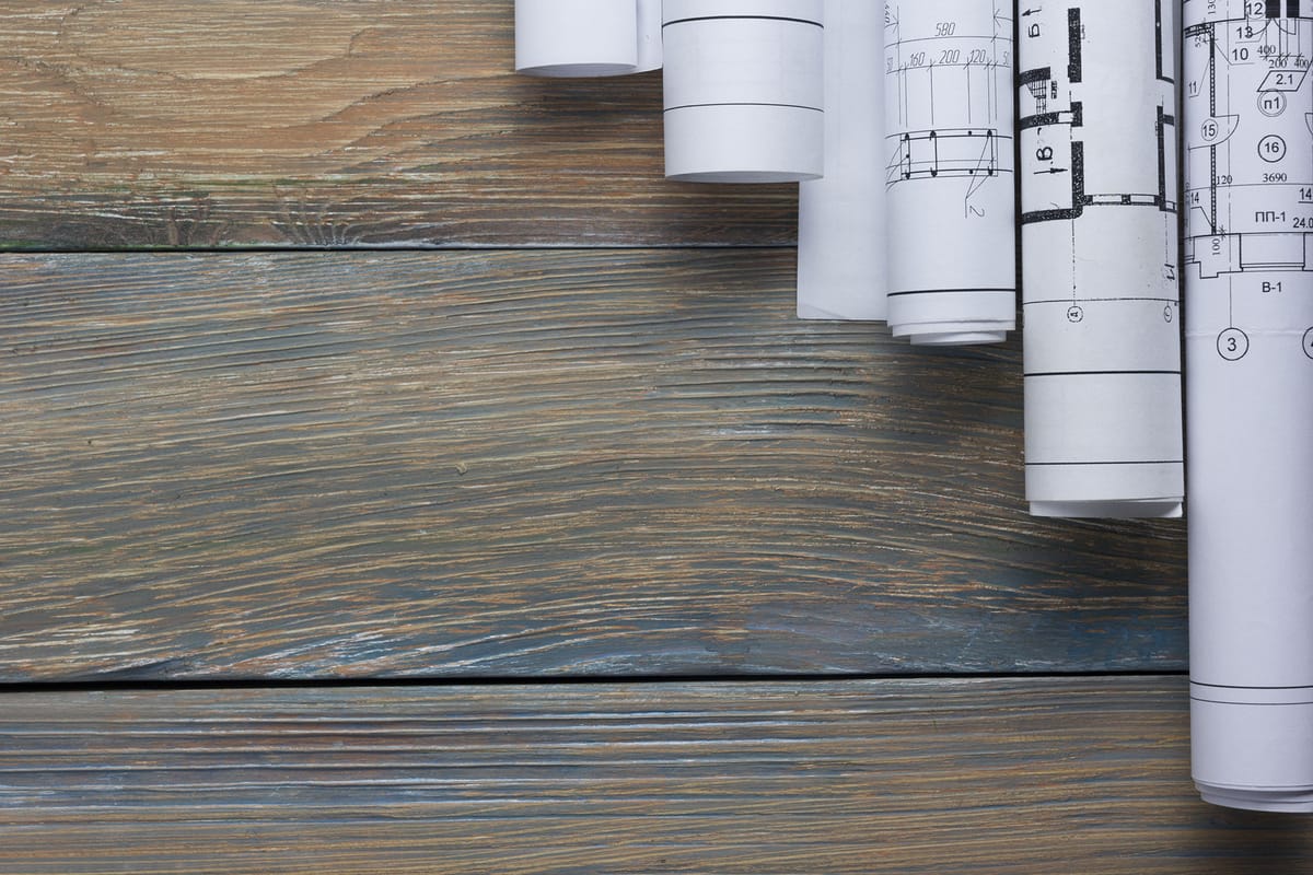 Rolled architectural drawings lying on a wooden floor