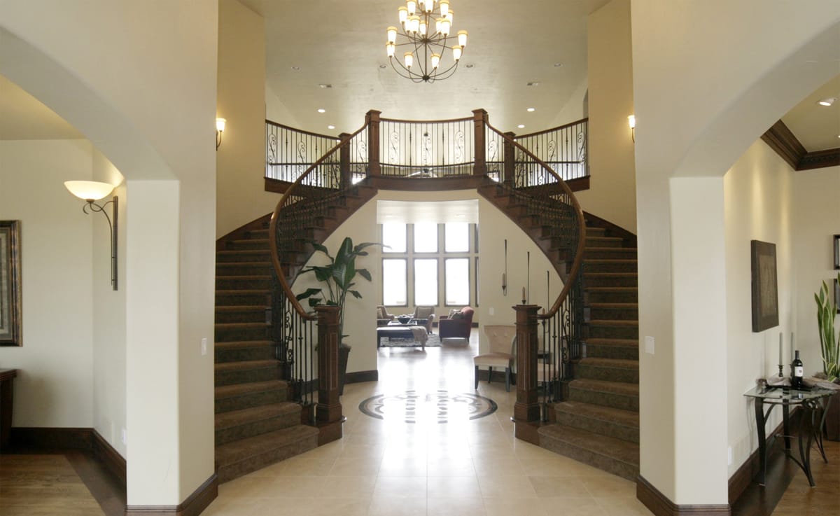 A two-storey entry hall with a curved double staircase and a chandelier