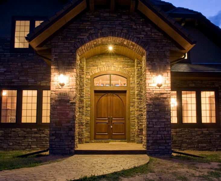 The arched stone entry of a Niwot Hills home glowing at twilight