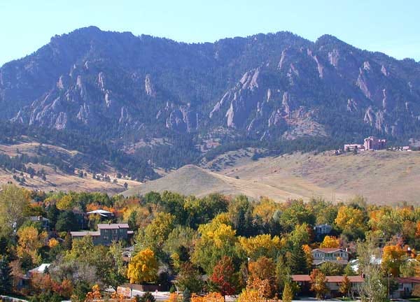 The Flatirons rising above the treetops of Boulder in autumn