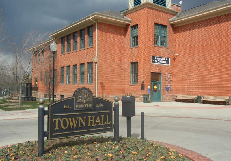 The brick Erie Town Hall behind its stone entrance sign