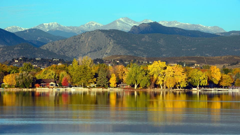Autumn trees reflected in a Loveland lake below the mountains